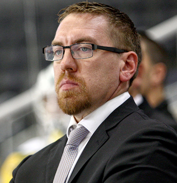 Portrait of Jay Varady, behind the bench in a dark suit and glasses